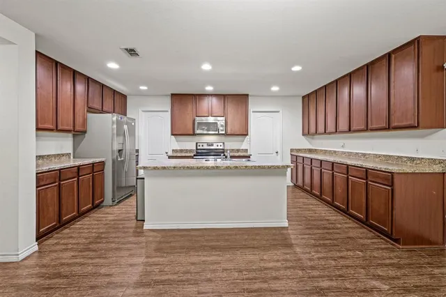 a kitchen with stainless steel appliances granite countertop a stove top oven a sink and dishwasher with wooden cabinets