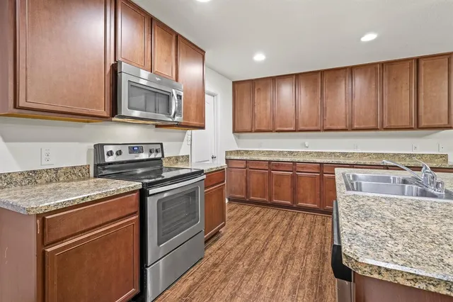 a kitchen with stainless steel appliances granite countertop wooden cabinets a stove top oven a sink and dishwasher