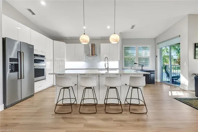 a kitchen with stainless steel appliances kitchen island granite countertop a table chairs sink and cabinets