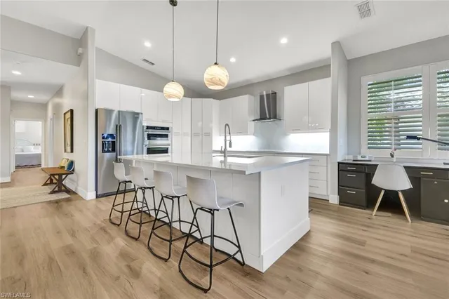 an open kitchen with wooden floor and stainless steel appliances