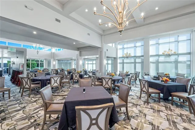 a room with lots of tables a large window and chairs