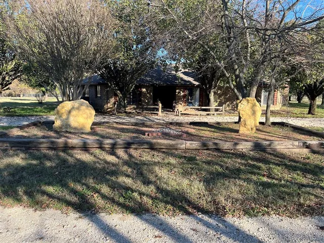 a view of a tree with fire pit next to a yard