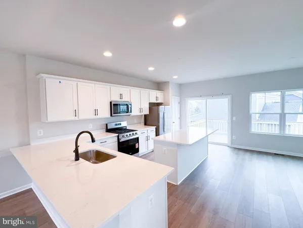 a kitchen with stainless steel appliances granite countertop a sink a stove and a wooden floors