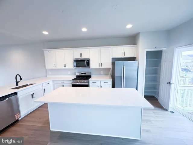 a large kitchen with stainless steel appliances a refrigerator stove microwave and sink