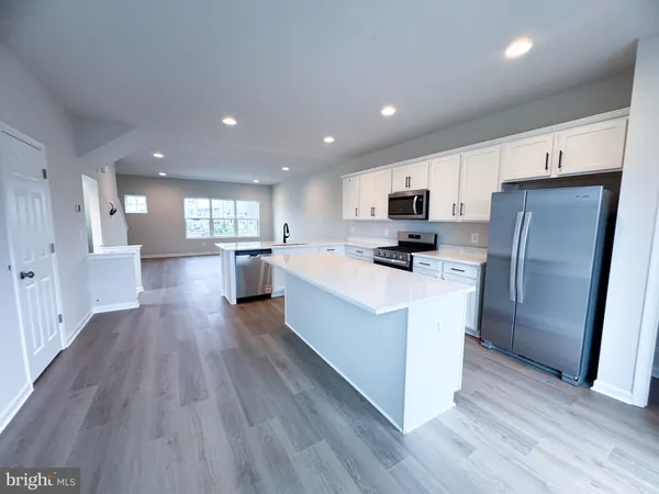 a large kitchen with stainless steel appliances granite countertop a stove top oven a refrigerator a sink and dishwasher with wooden floor
