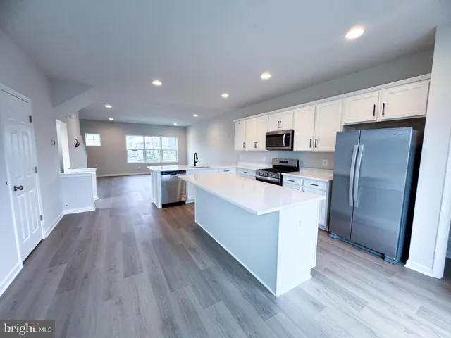 a large kitchen with stainless steel appliances granite countertop a stove top oven a refrigerator a sink and dishwasher with wooden floor