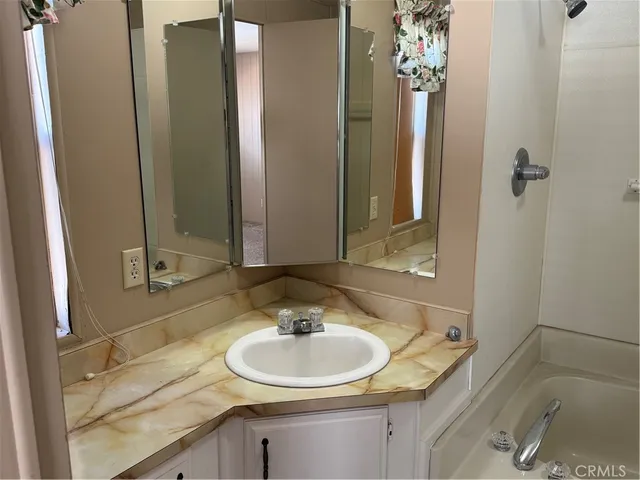 a bathroom with a sink double vanity granite tub shower and a mirror