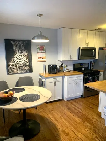 a kitchen with stainless steel appliances a stove a sink a microwave a dining table and chairs