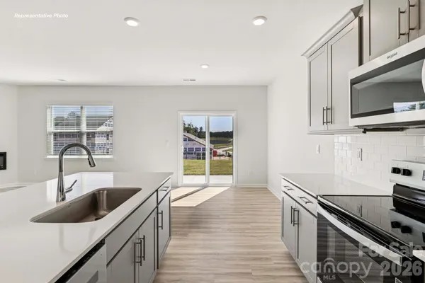a kitchen with stainless steel appliances kitchen island granite countertop a sink and a stove top oven with wooden floor