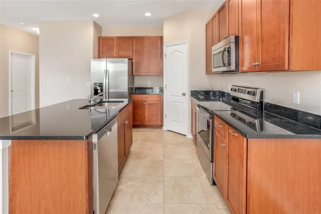 a kitchen with stainless steel appliances granite countertop a sink a stove and a refrigerator