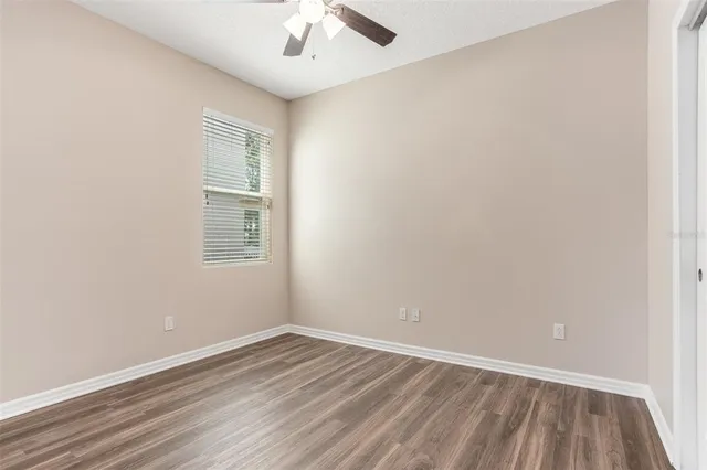 an empty room with a window and a ceiling fan