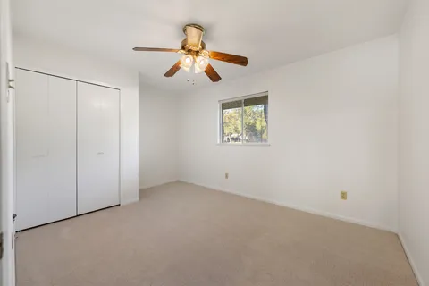 an empty room with windows and fan