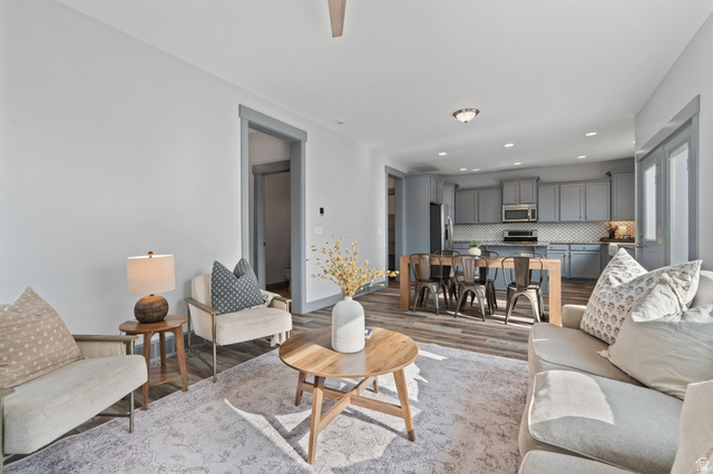 7822 North Copperbend Road Eagle Mountain, UT 84005 - Photo 11 of 46 Open-concept living area featuring wood-finish flooring, recessed lighting, and a modern kitchen with gray cabinetry and a tiled backsplash