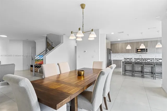 a kitchen with a table chairs refrigerator and wooden floor