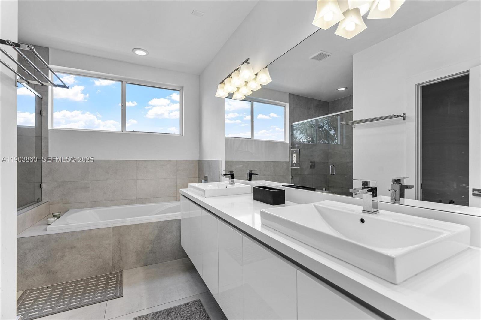 10330 Northwest 68th Street Doral, FL 33178 - Photo 29 of 60 a bathroom with a sink a large mirror and a bathtub