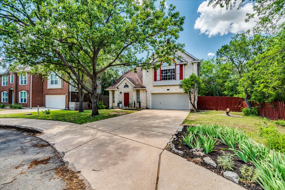 9300 Tea Rose Trail Austin, TX 78748 - Photo 5 of 33 A welcoming stone facade with a red front door and a mature tree providing natural shade enhance this home's curb appeal.