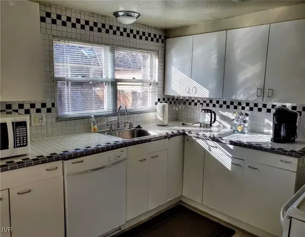 a kitchen with granite countertop a sink a window and cabinets