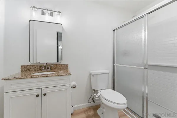 a bathroom with a granite countertop toilet sink and mirror