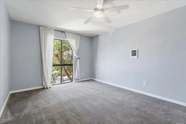 an empty room with windows and chandelier fan