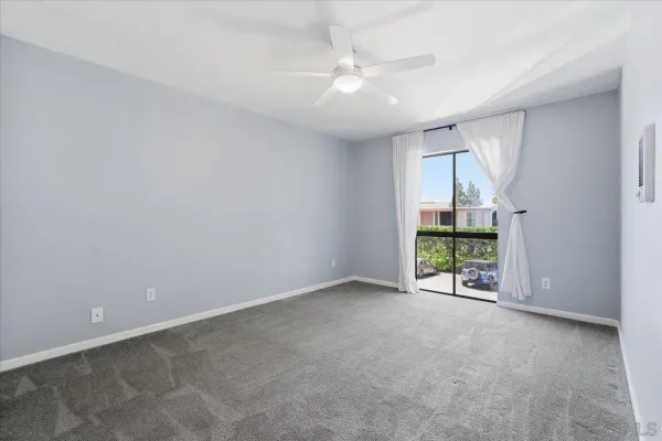 an empty room with windows and chandelier fan