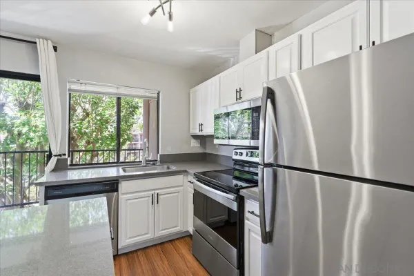 a kitchen with a refrigerator a sink and white cabinets