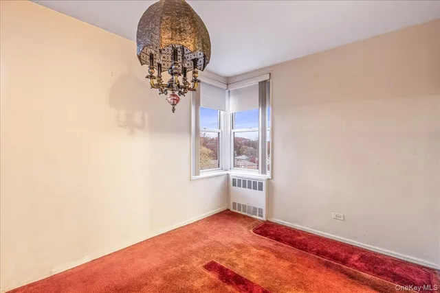 an empty room with a chandelier fan and windows