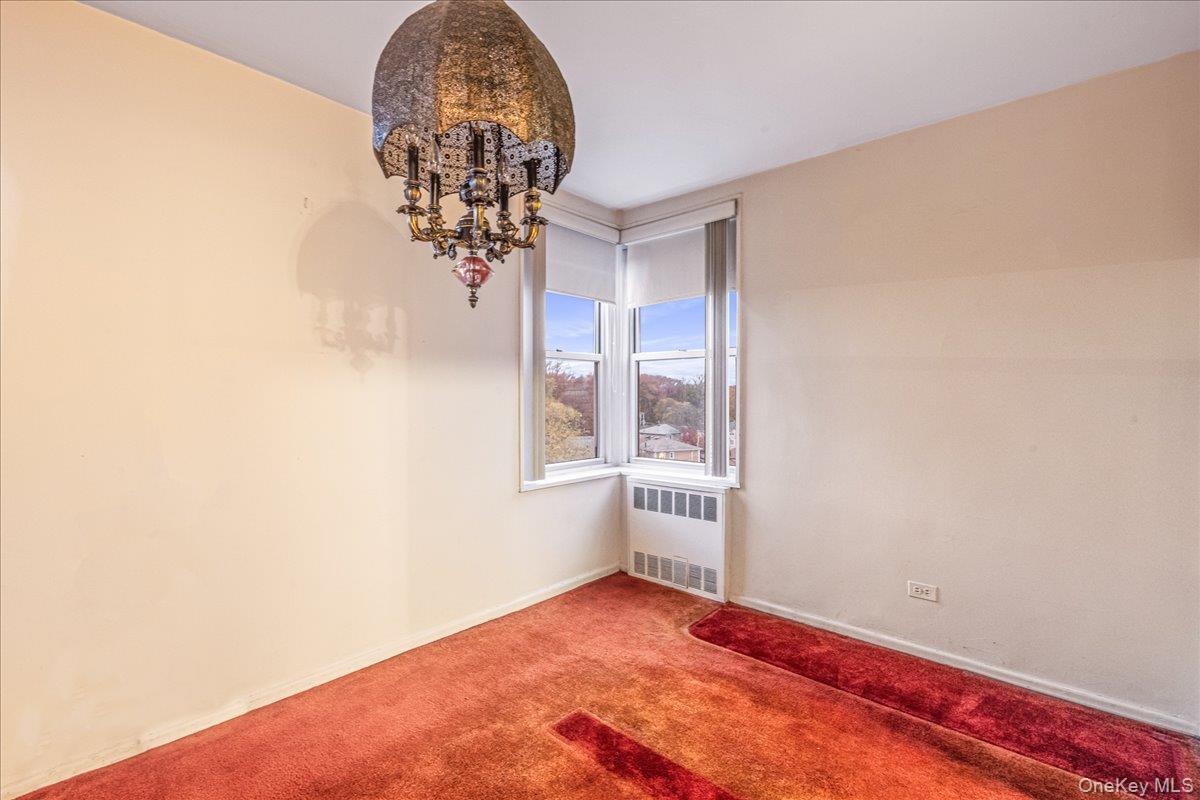 209-25 18th Avenue, Unit 6D Queens, NY 11360 - Photo 11 of 26 an empty room with a chandelier fan and windows