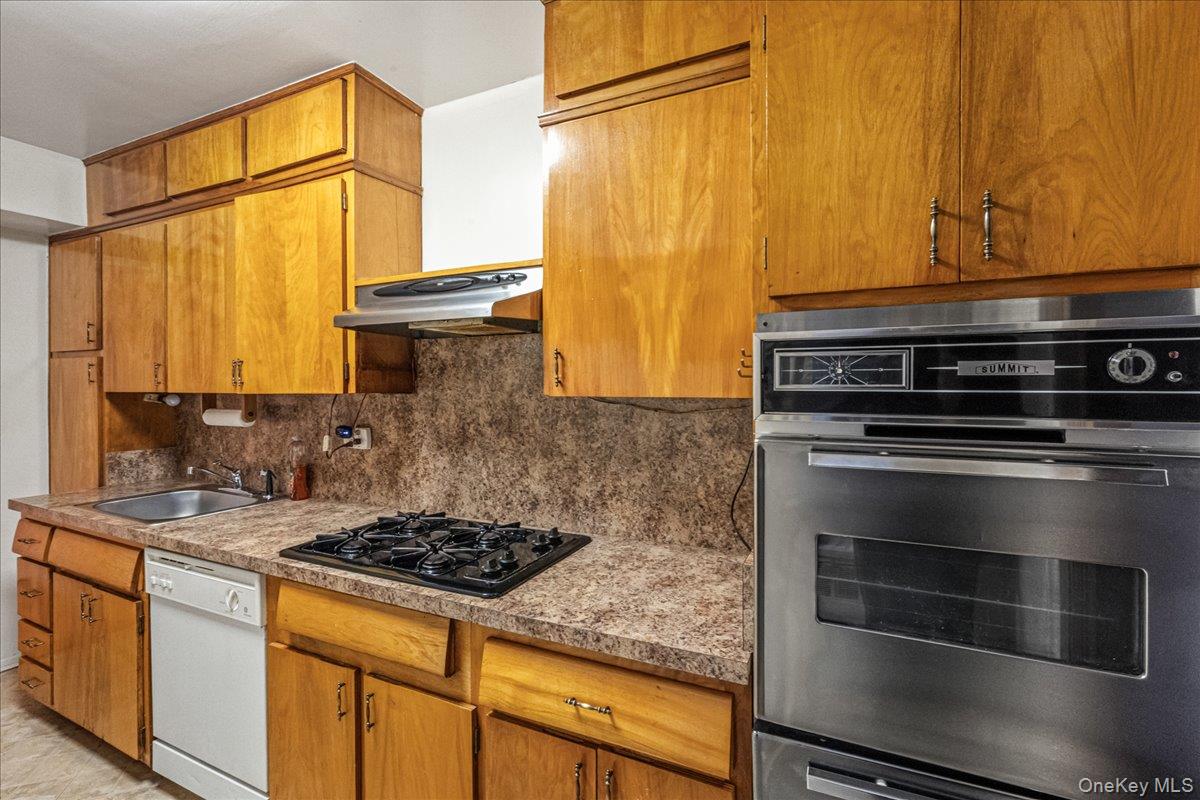 209-25 18th Avenue, Unit 6D Queens, NY 11360 - Photo 12 of 26 a kitchen with stainless steel appliances granite countertop a stove and a refrigerator