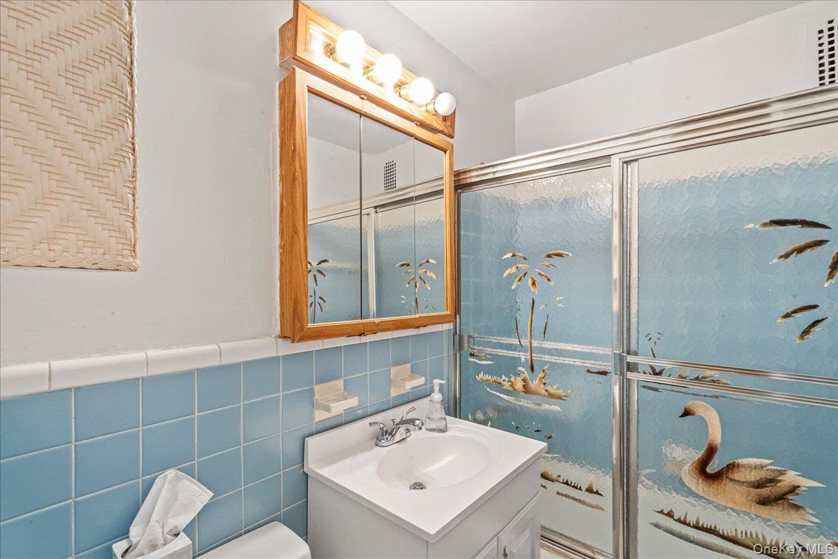209-25 18th Avenue, Unit 6D Queens, NY 11360 - Photo 14 of 26 a bathroom with a sink mirror and toilet