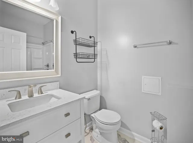 a bathroom with a granite countertop sink mirror vanity and toilet