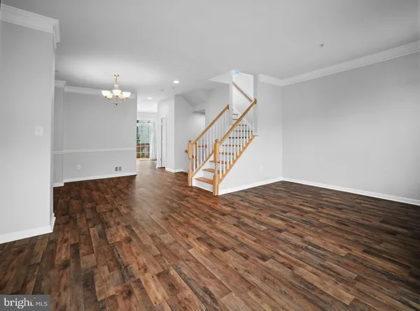 a view of an empty room with wooden floor and stairs