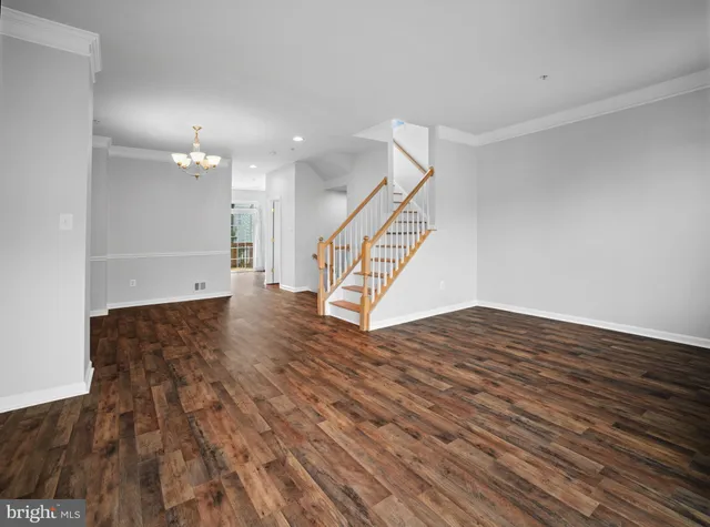 a view of an empty room with wooden floor and stairs