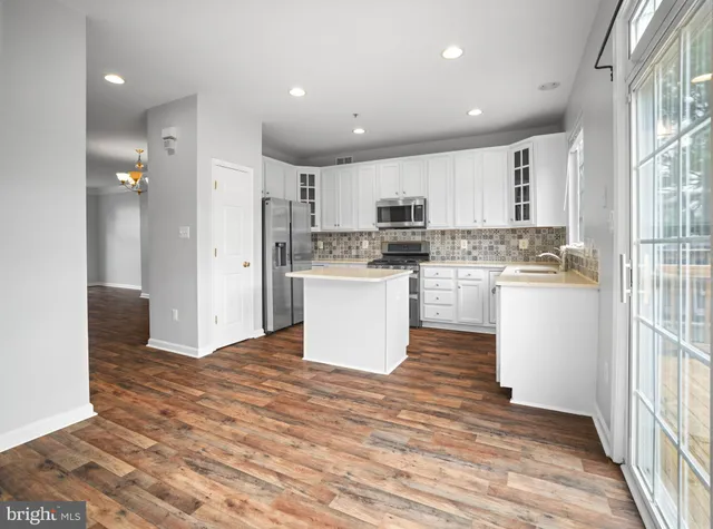 a kitchen with kitchen island a sink a stove a refrigerator and white cabinets