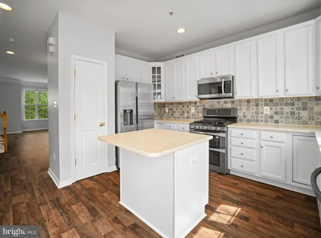 a kitchen with stainless steel appliances white cabinets a sink a stove a refrigerator and microwave
