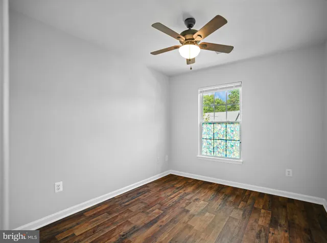 an empty room with window and ceiling fan