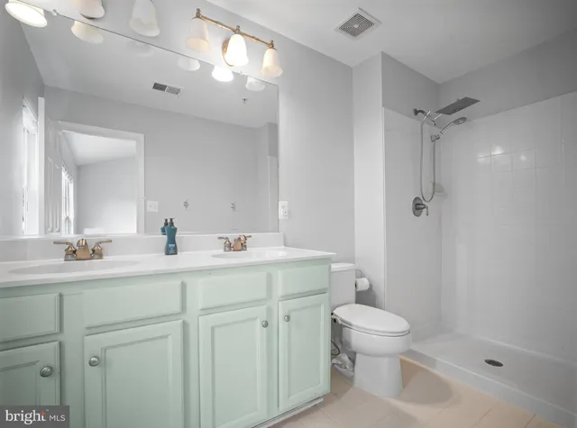 a bathroom with a toilet a sink a mirror a shower a vanity and window