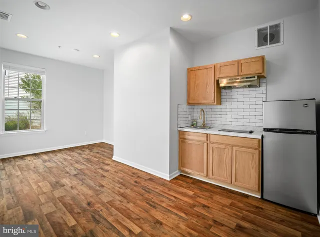 a kitchen with granite countertop a sink cabinets and wooden floor