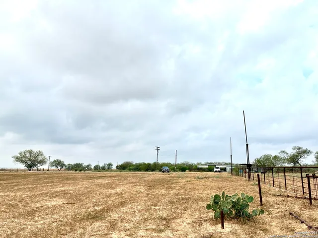 a view of a dry yard with wooden fence