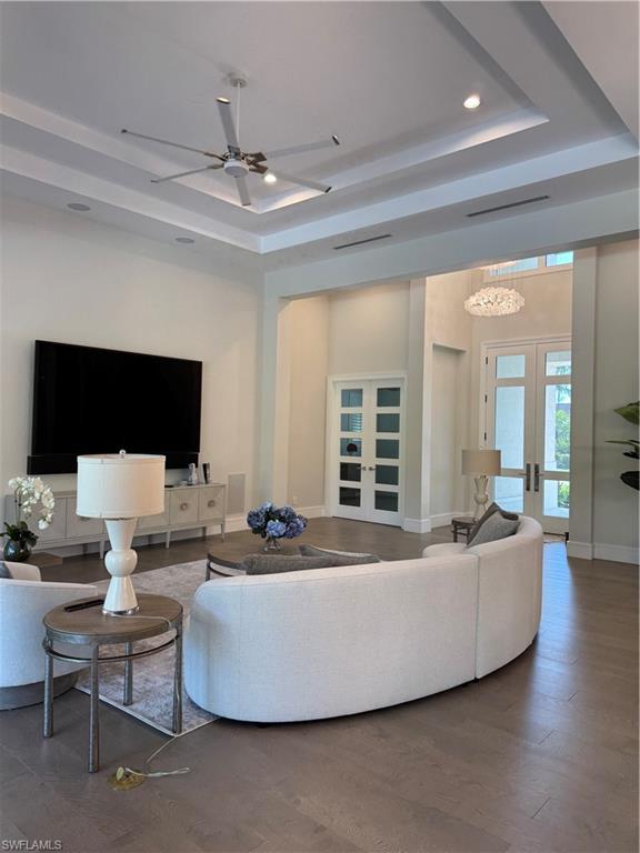569 Neapolitan Way Naples, FL 34103 - Photo 4 of 50 Living room with french doors, baseboards, a raised ceiling, and a ceiling fan