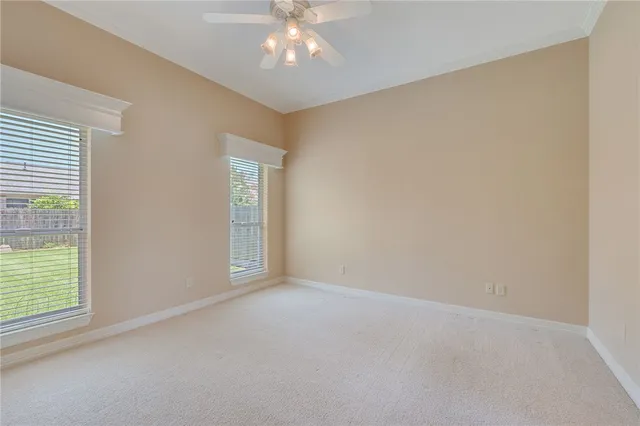 an empty room with windows and chandelier fan