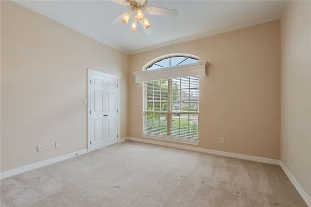 an empty room with a chandelier fan and a window