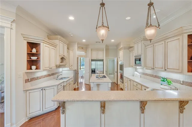 a view of a kitchen with kitchen island a sink stainless steel appliances and cabinets