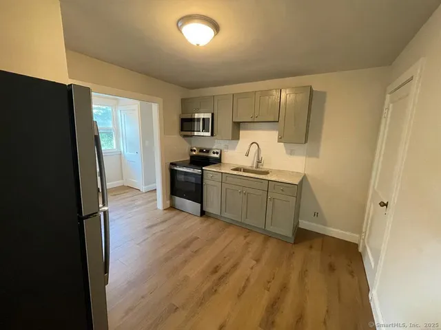a kitchen with stainless steel appliances a sink a stove a refrigerator and cabinets