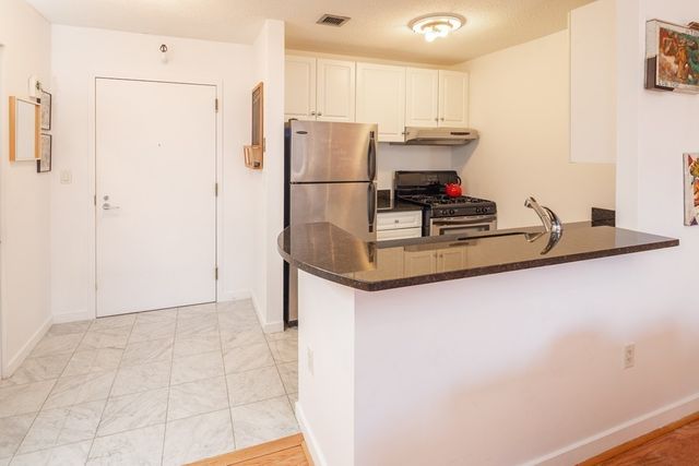 a kitchen with stainless steel appliances granite countertop a refrigerator a stove and a sink