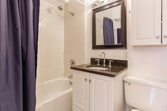 a bathroom with a granite countertop sink mirror vanity and toilet