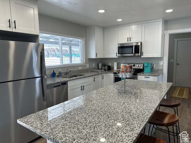 702 North 100 West Logan, UT 84321 - Photo 12 of 58 Kitchen featuring a textured ceiling, white cabinets, stainless steel appliances, a sink, and dark wood-style floors