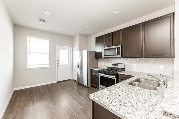 a kitchen with stainless steel appliances granite countertop a sink stove microwave and refrigerator