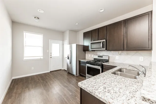 a kitchen with stainless steel appliances granite countertop a sink stove microwave and refrigerator
