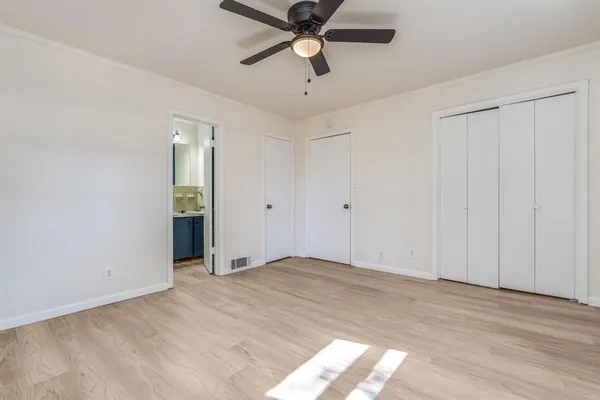 a view of an empty room and chandelier fan