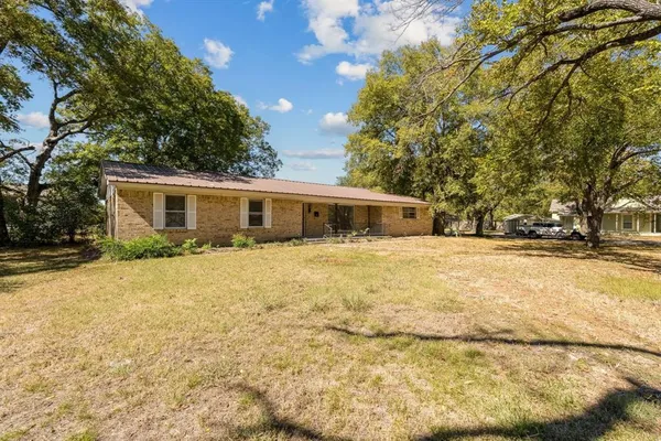 a front view of house with yard and trees in the background